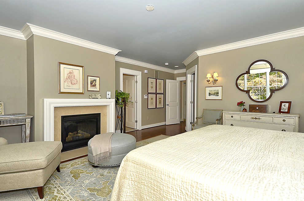 Modelo de dormitorio principal tradicional renovado grande con paredes beige, moqueta, todas las chimeneas, marco de chimenea de piedra y suelo marrón