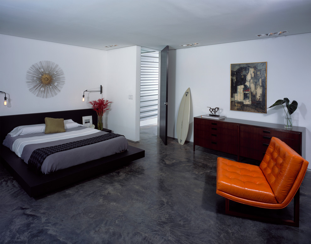 Example of a minimalist concrete floor and black floor bedroom design in New Orleans with white walls