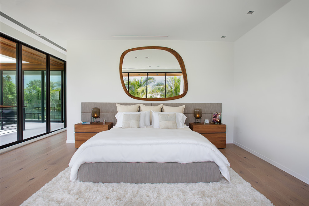 Imagen de dormitorio contemporáneo con paredes blancas, suelo de madera clara y suelo marrón