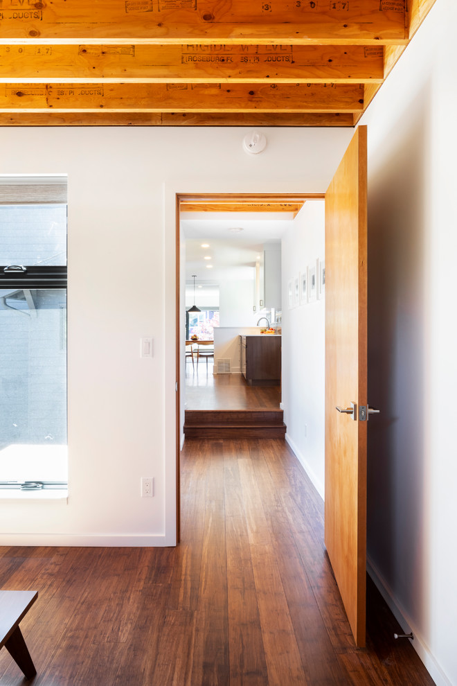 Mittelgroßes Modernes Hauptschlafzimmer ohne Kamin mit weißer Wandfarbe und braunem Holzboden in Seattle