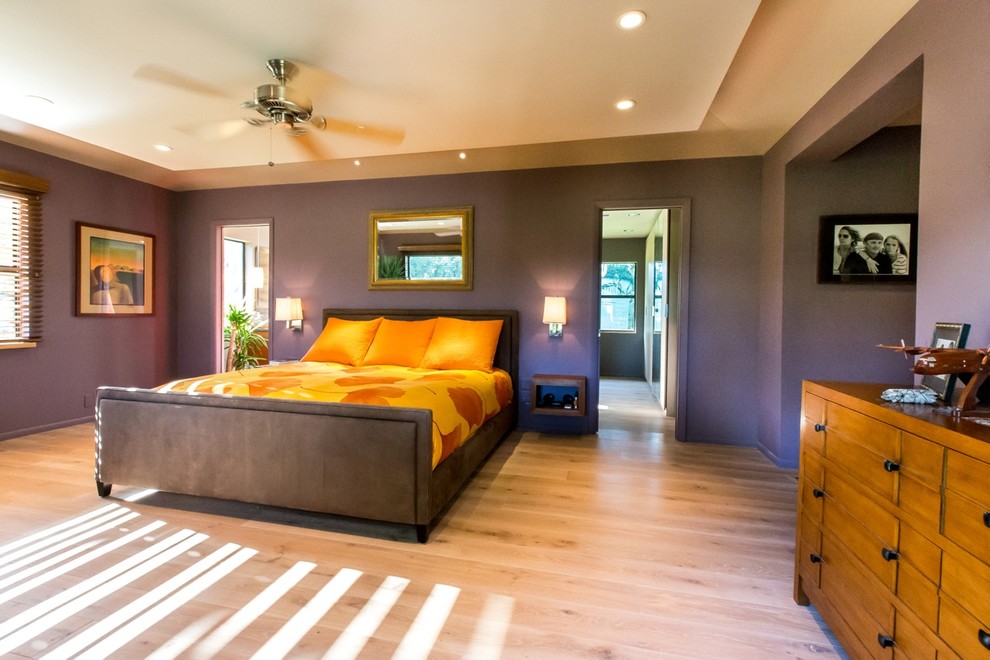 Cette image montre une chambre parentale design de taille moyenne avec un mur violet et parquet clair.