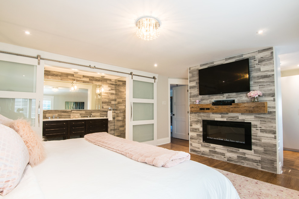 モントリオールにある広いエクレクティックスタイルのおしゃれな主寝室 (グレーの壁、濃色無垢フローリング、吊り下げ式暖炉、タイルの暖炉まわり、茶色い床) のレイアウト