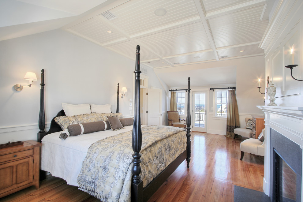 Modelo de habitación de invitados costera de tamaño medio con paredes azules, suelo de madera en tonos medios, todas las chimeneas y marco de chimenea de madera