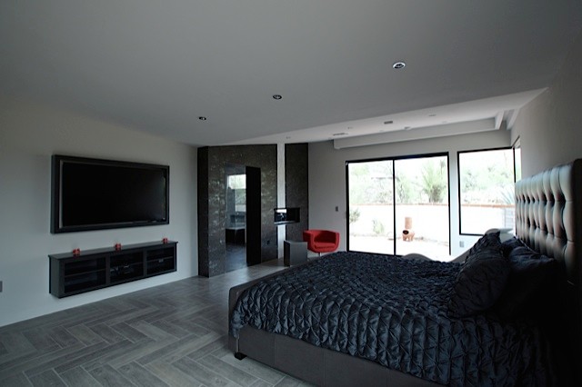 Imagen de dormitorio principal actual de tamaño medio con paredes grises, suelo de baldosas de cerámica, chimenea lineal y marco de chimenea de baldosas y/o azulejos