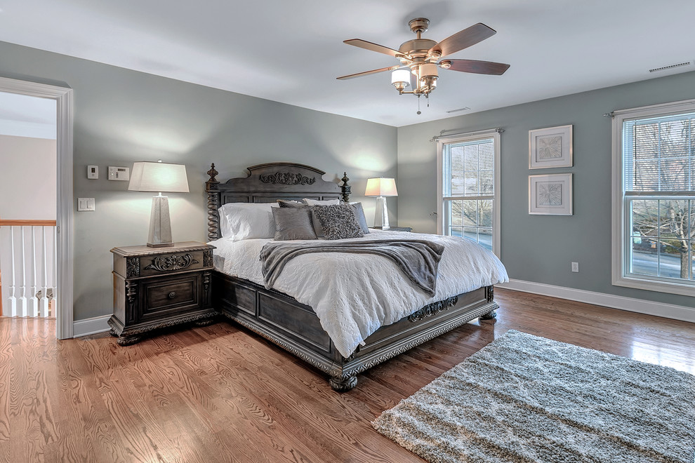 Modelo de dormitorio principal clásico renovado de tamaño medio sin chimenea con paredes grises, suelo de madera en tonos medios y suelo marrón