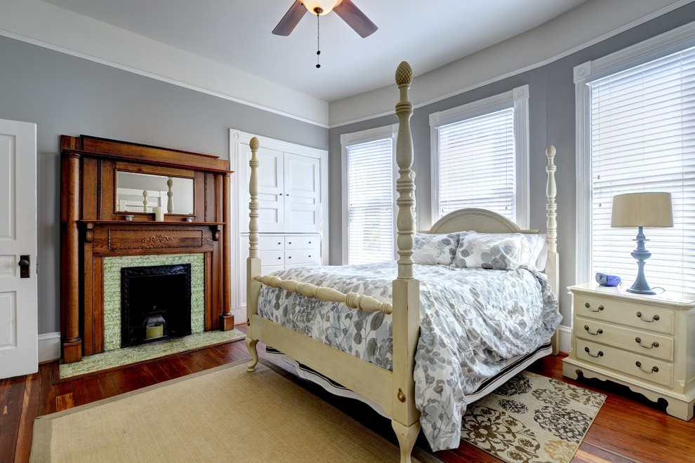 Diseño de dormitorio clásico con paredes grises, marco de chimenea de baldosas y/o azulejos y todas las chimeneas