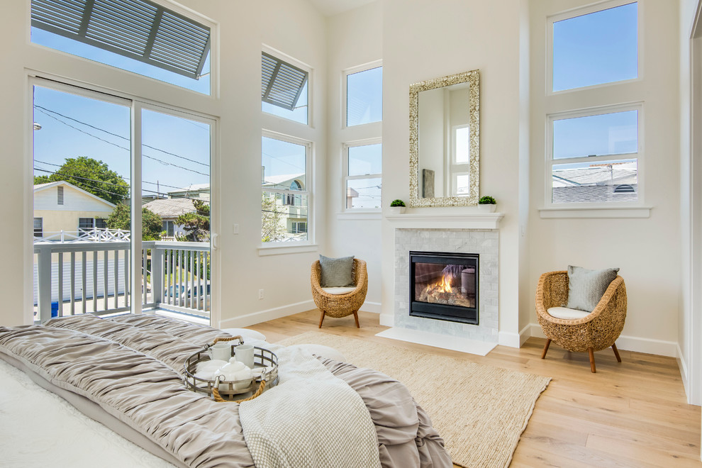 ロサンゼルスにある中くらいなビーチスタイルのおしゃれな主寝室 (白い壁、淡色無垢フローリング、標準型暖炉、石材の暖炉まわり、ベージュの床) のレイアウト