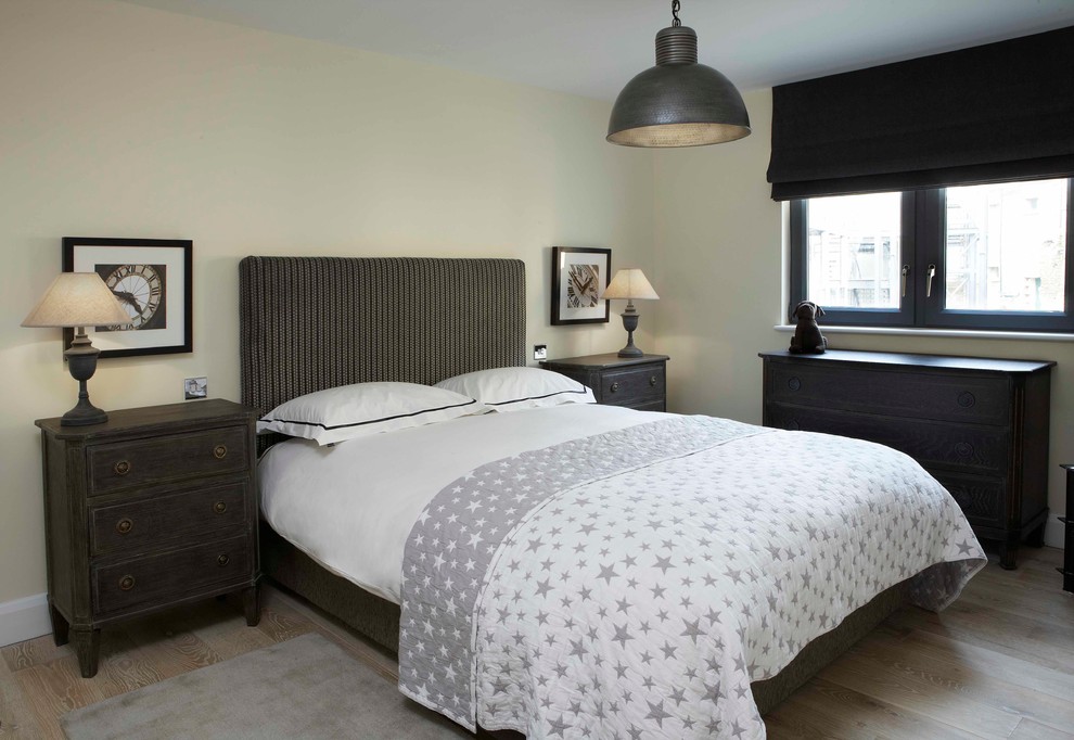 This is an example of an urban bedroom in Oxfordshire with beige walls and medium hardwood flooring.