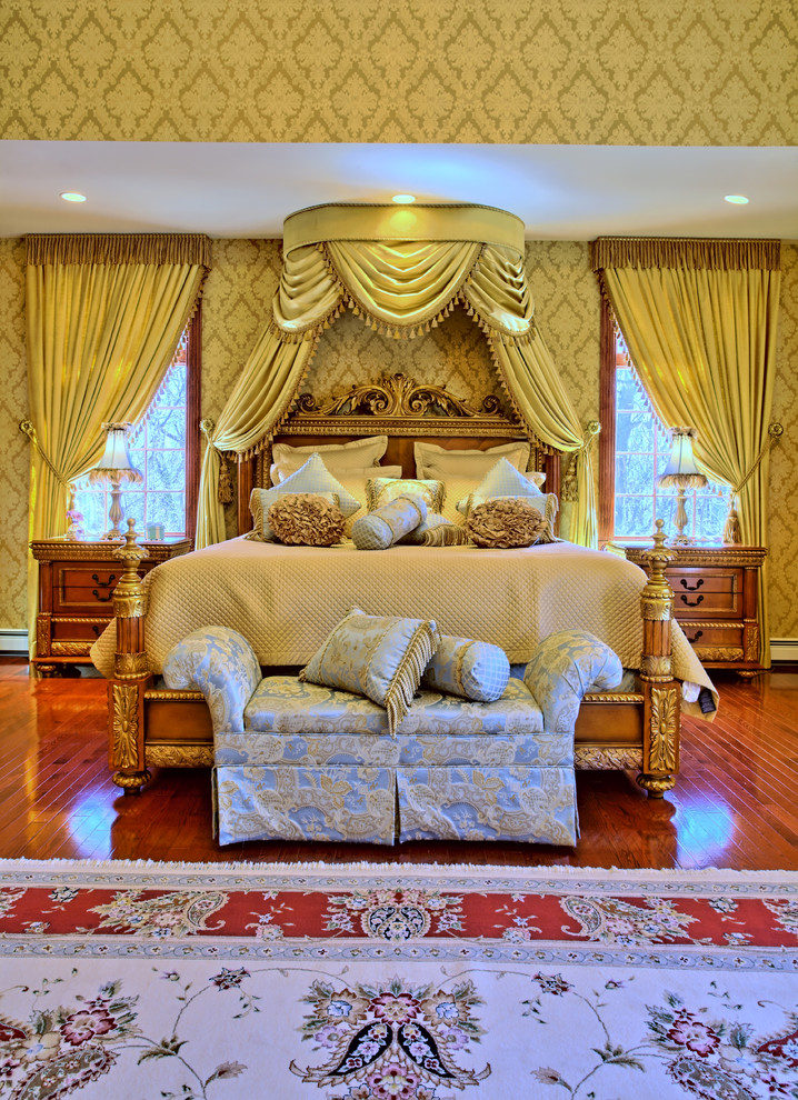Geräumiges Klassisches Hauptschlafzimmer mit gelber Wandfarbe, dunklem Holzboden und Kaminumrandung aus Stein in Miami