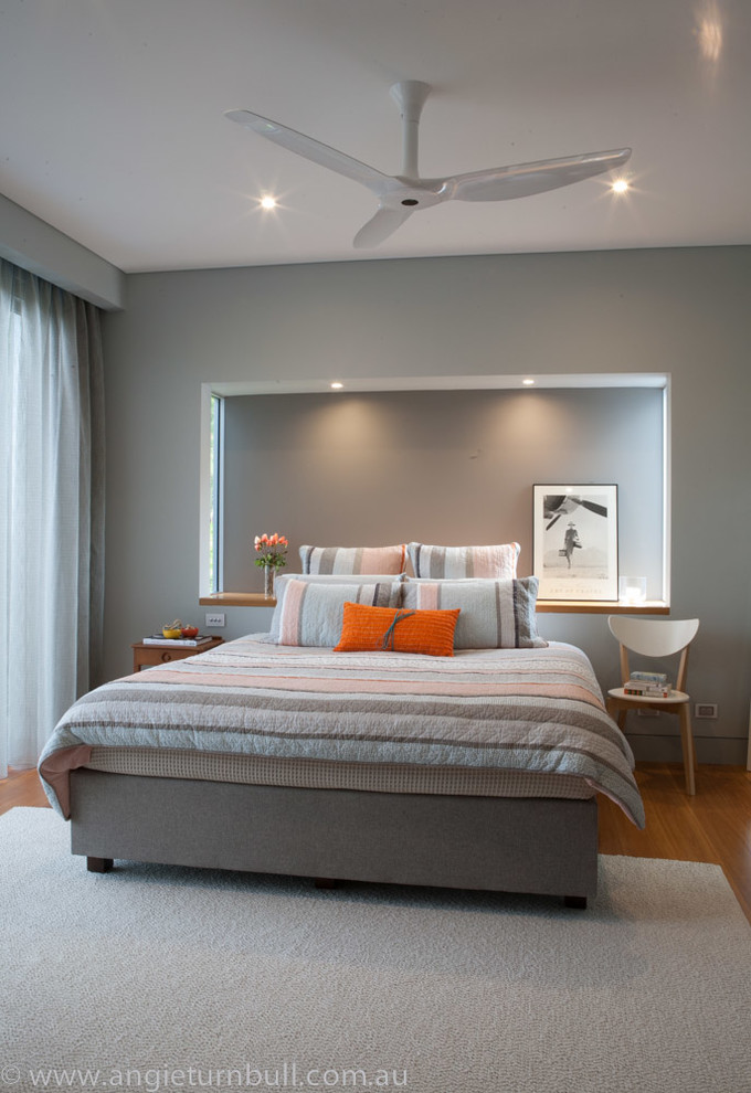 This is an example of a medium sized contemporary master bedroom in Sydney with grey walls, medium hardwood flooring and no fireplace.