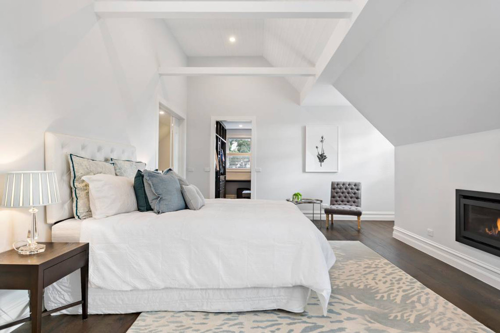 Großes Klassisches Hauptschlafzimmer mit weißer Wandfarbe, dunklem Holzboden, Kamin, verputzter Kaminumrandung und braunem Boden in Melbourne
