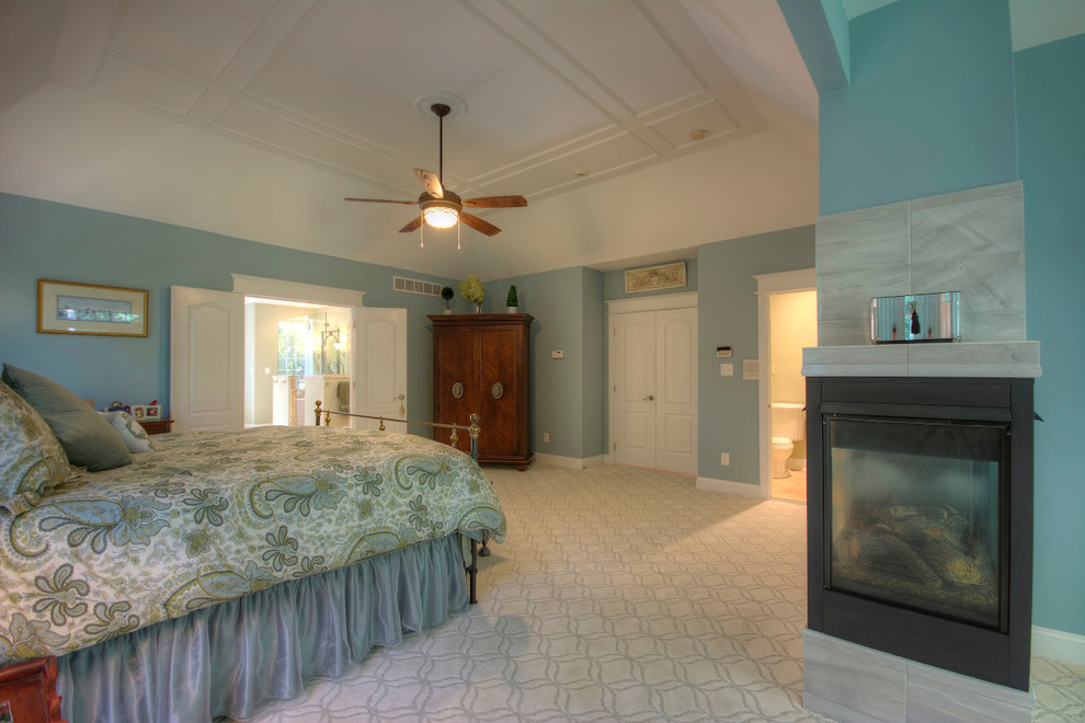 Aménagement d'une grande chambre classique avec un mur bleu, une cheminée double-face et un manteau de cheminée en pierre.
