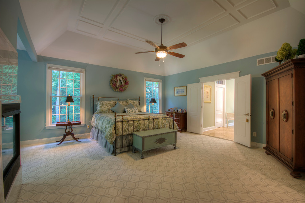 Стильный дизайн: большая хозяйская спальня в стиле неоклассика (современная классика) с синими стенами, ковровым покрытием, двусторонним камином и фасадом камина из камня - последний тренд