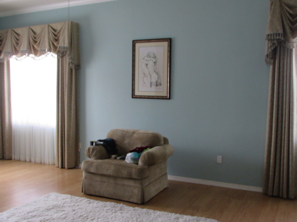 Modelo de dormitorio principal clásico de tamaño medio con paredes azules y suelo de madera en tonos medios
