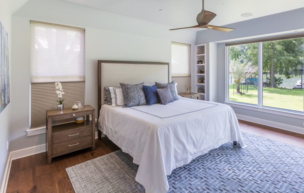 Idée de décoration pour une chambre parentale minimaliste de taille moyenne avec un mur gris, un sol en bois brun, une cheminée standard, un manteau de cheminée en carrelage et un sol marron.
