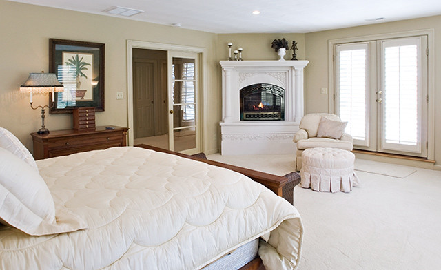 Réalisation d'une chambre tradition de taille moyenne avec un mur blanc, une cheminée d'angle, un manteau de cheminée en plâtre et un sol beige.
