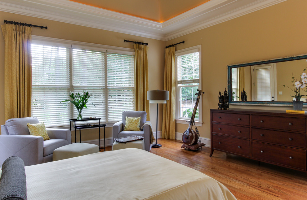 Example of a mid-sized transitional master medium tone wood floor bedroom design in Raleigh with yellow walls and no fireplace