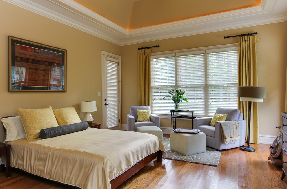 Imagen de dormitorio principal tradicional renovado de tamaño medio sin chimenea con paredes amarillas y suelo de madera en tonos medios