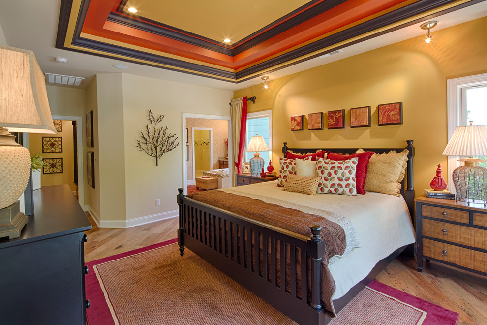 Ispirazione per una camera da letto tradizionale con pareti gialle e pavimento in legno massello medio