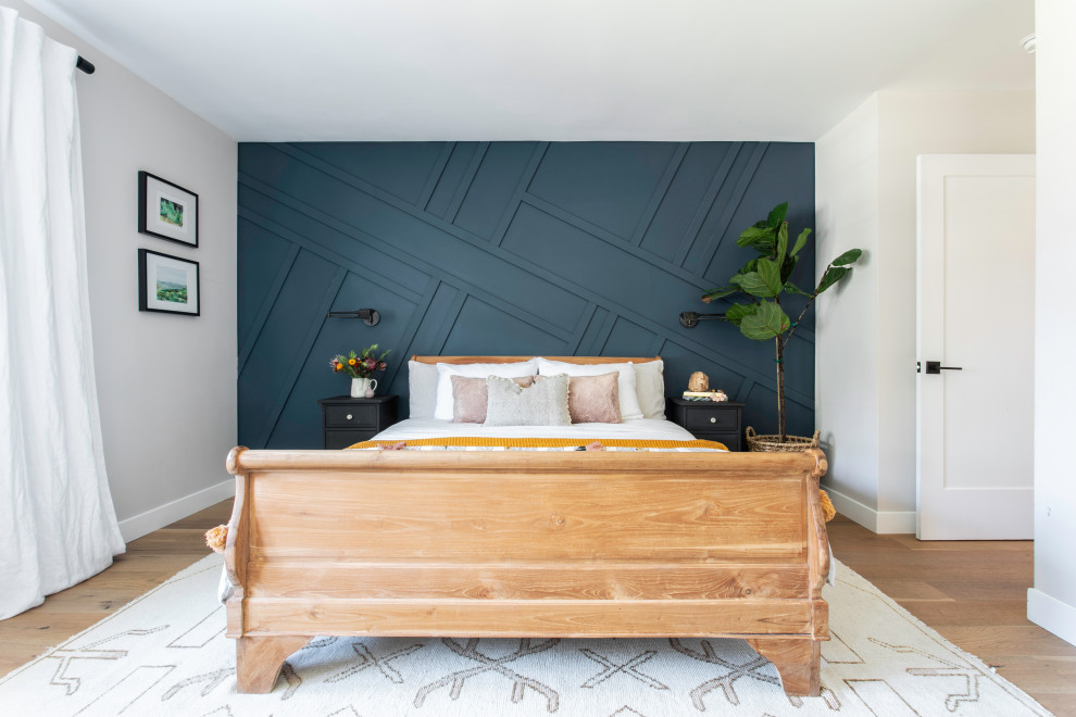 Imagen de dormitorio principal de estilo de casa de campo de tamaño medio con paredes azules, suelo de madera clara y panelado