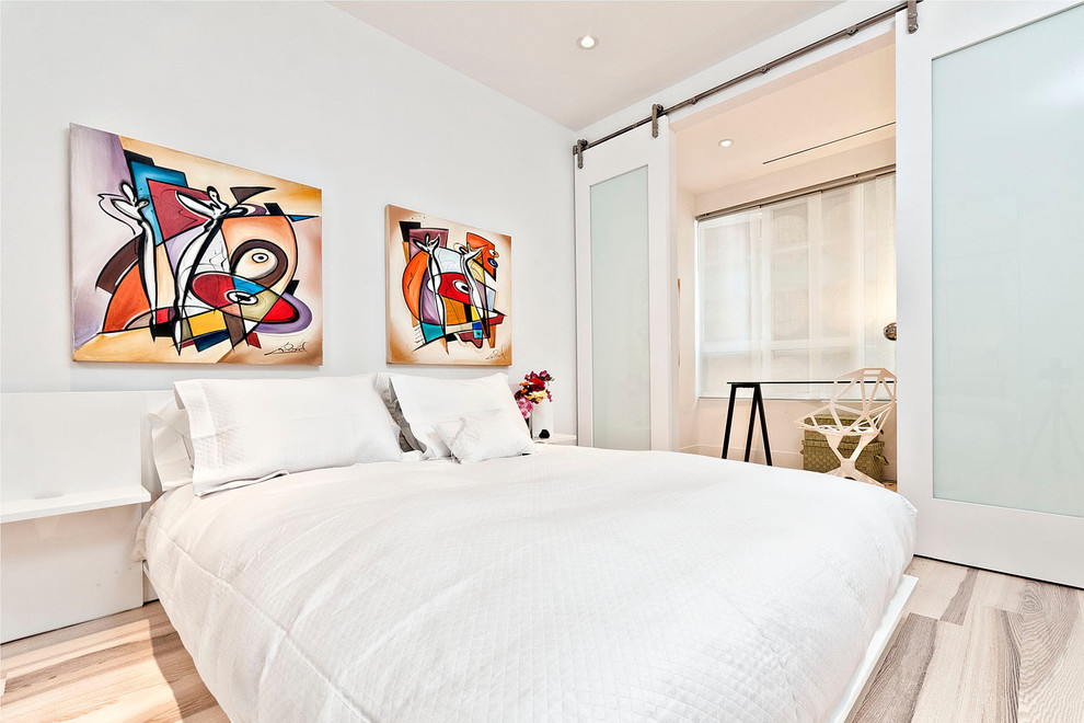 Immagine di una camera da letto minimalista con pareti bianche e parquet chiaro
