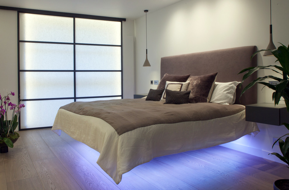 Inspiration for a contemporary master light wood floor bedroom remodel in London with white walls and no fireplace