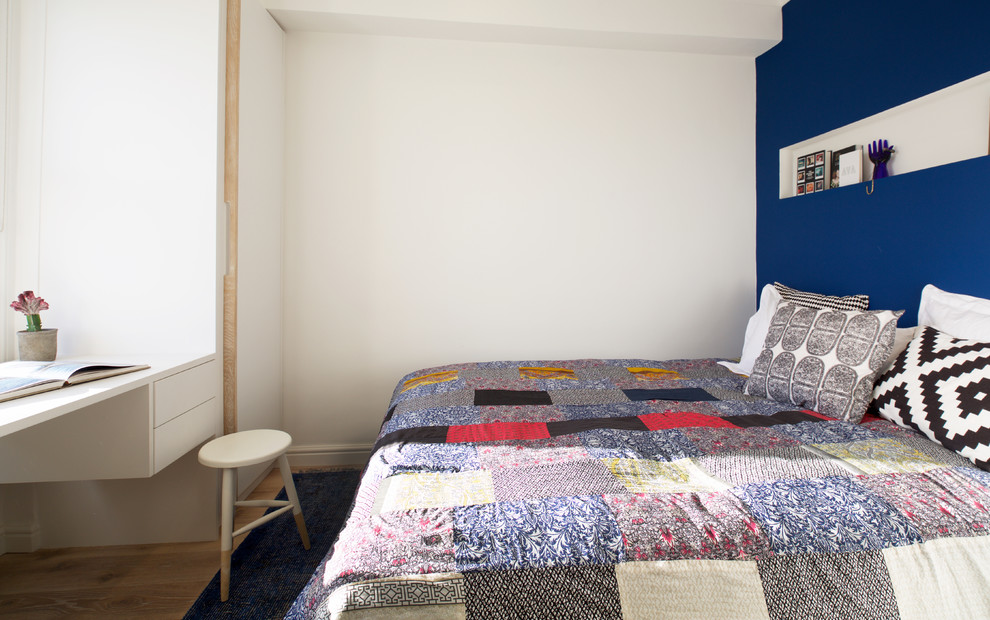 Small contemporary master bedroom in London with blue walls and light hardwood flooring.