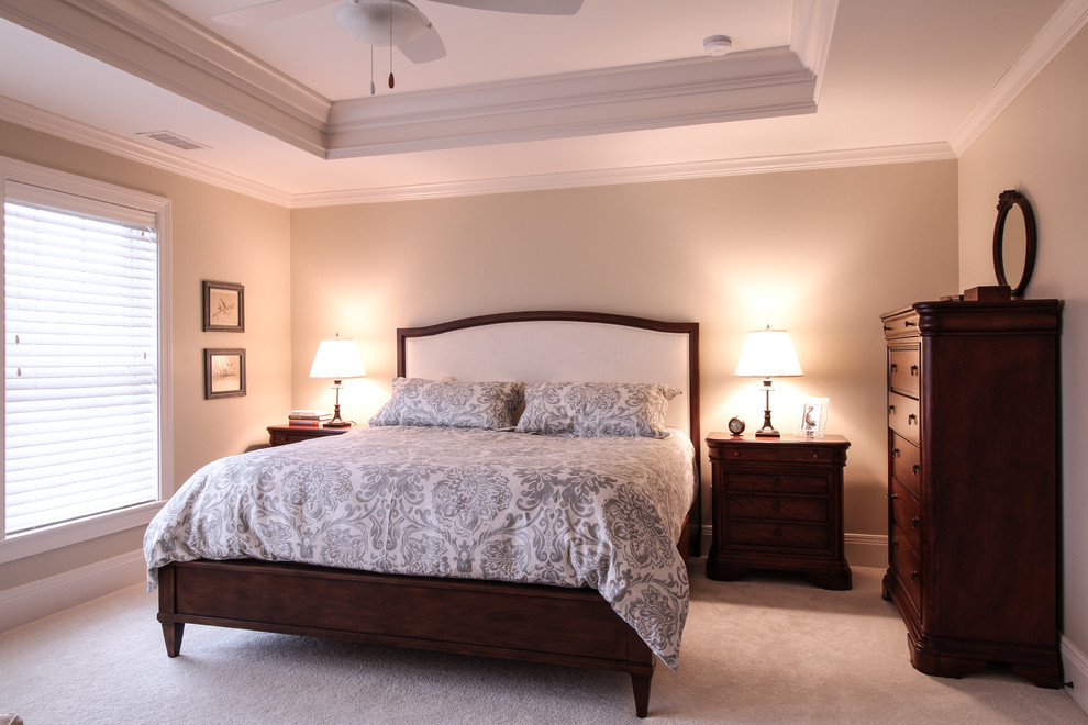 Modelo de dormitorio principal clásico renovado de tamaño medio con paredes beige y moqueta
