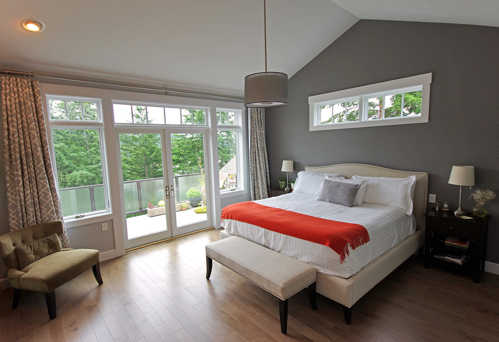 This is an example of a large contemporary master bedroom with grey walls, medium hardwood flooring, a standard fireplace, a tiled fireplace surround and brown floors.
