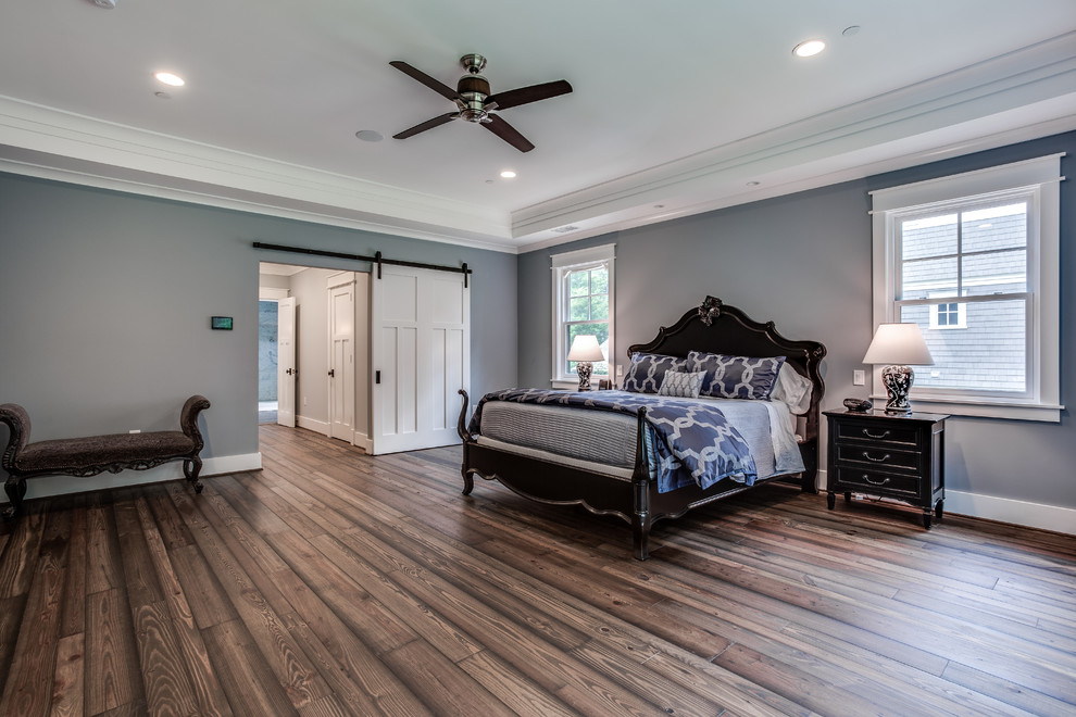 Modelo de dormitorio principal de estilo americano grande con paredes azules y suelo de madera en tonos medios