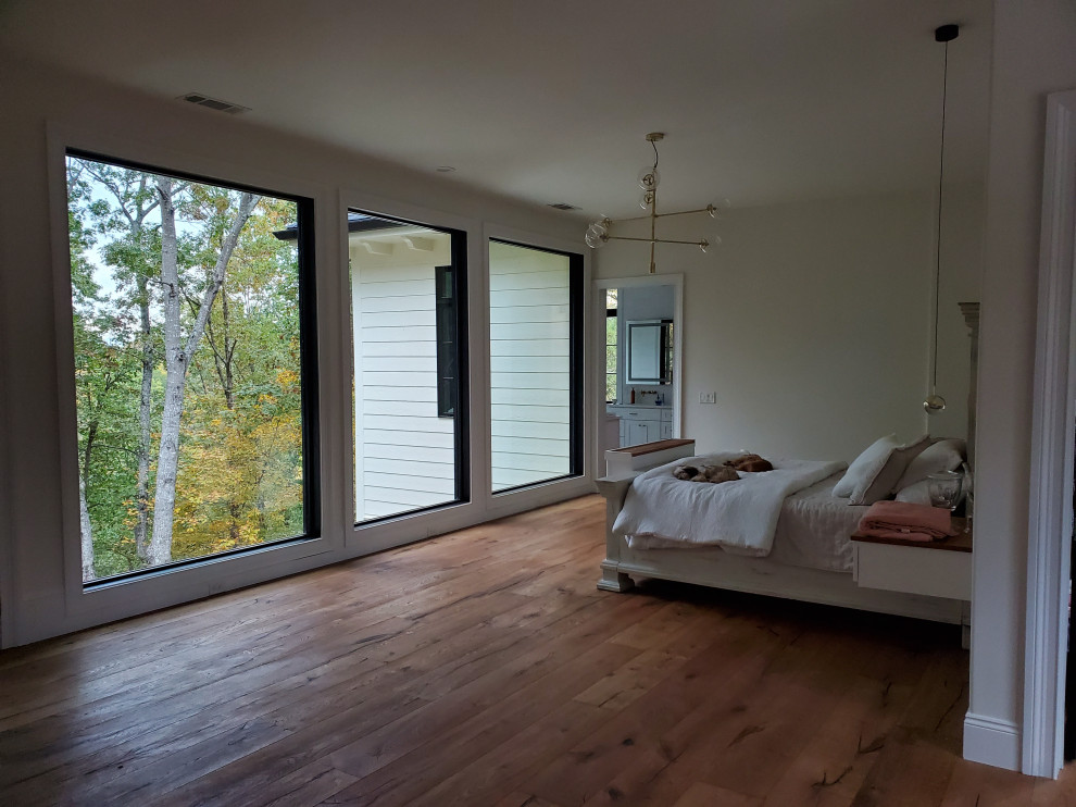 Ispirazione per un'ampia camera da letto stile loft minimalista con pareti beige e pavimento in legno massello medio