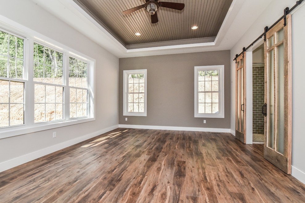 Large cottage master vinyl floor and brown floor bedroom photo in Other with gray walls and no fireplace
