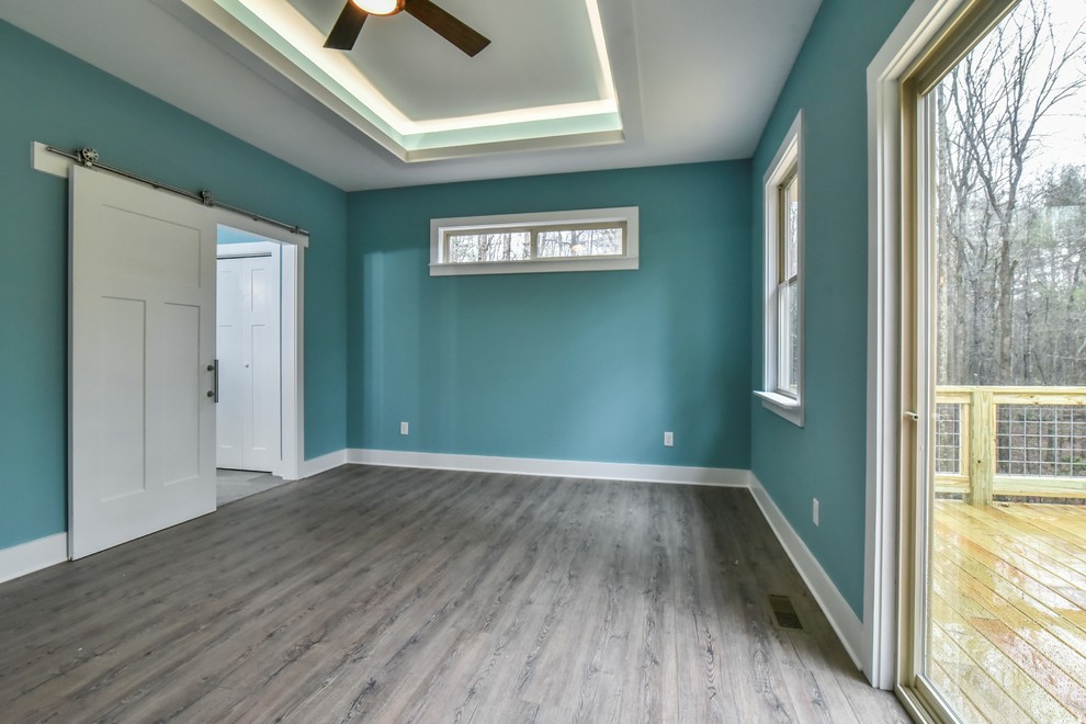 Modelo de dormitorio principal de estilo americano de tamaño medio sin chimenea con paredes azules, suelo vinílico y suelo marrón