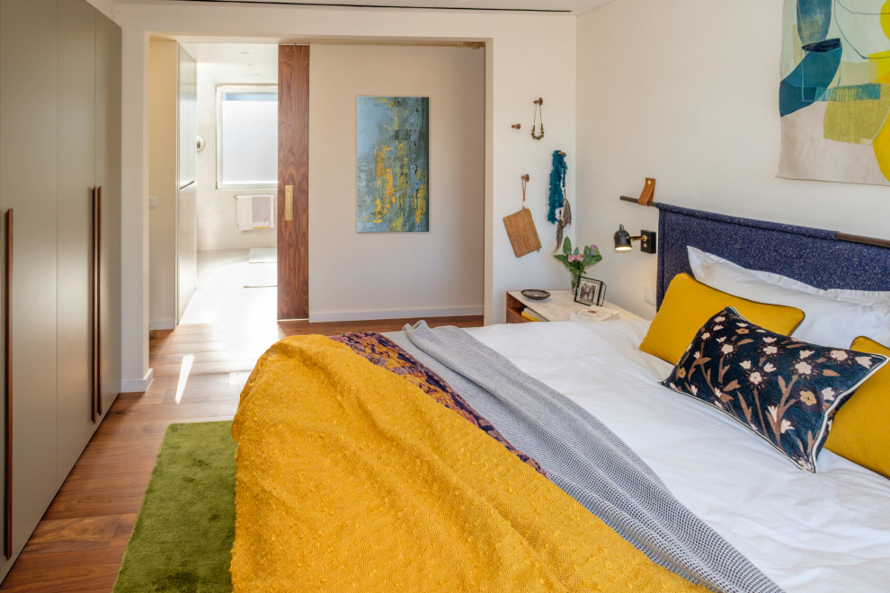 Foto de dormitorio principal actual de tamaño medio con paredes beige y suelo de madera en tonos medios