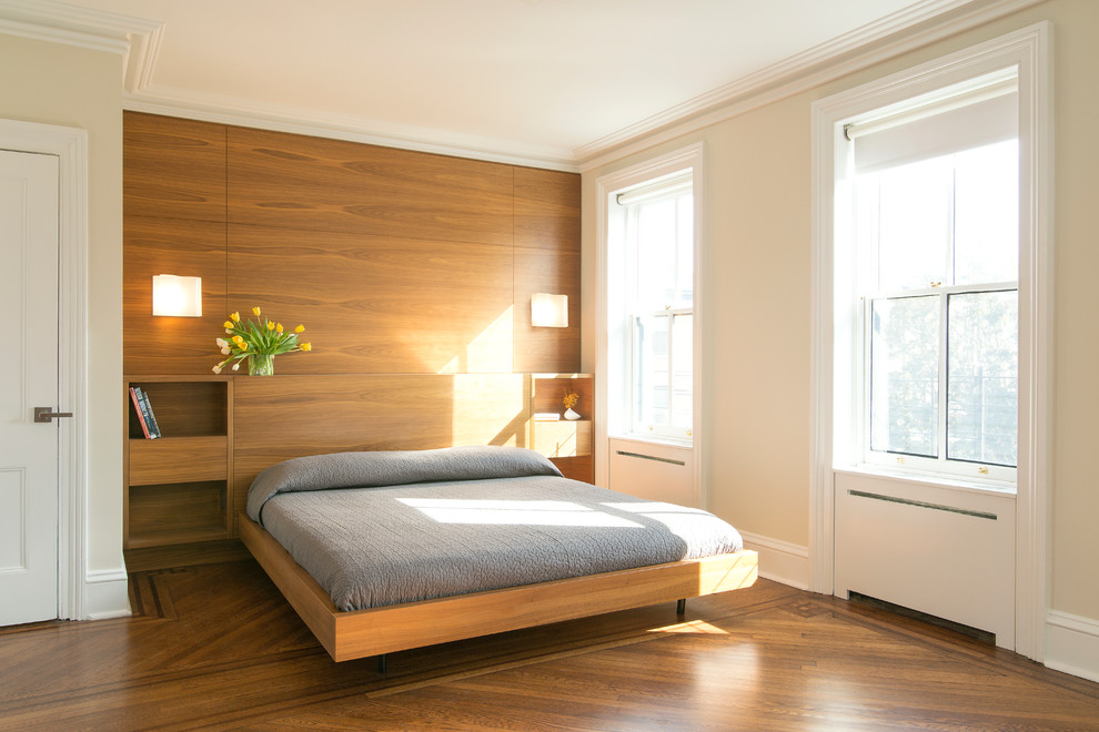Cette image montre une chambre parentale design de taille moyenne avec un mur beige, un sol en bois brun et aucune cheminée.