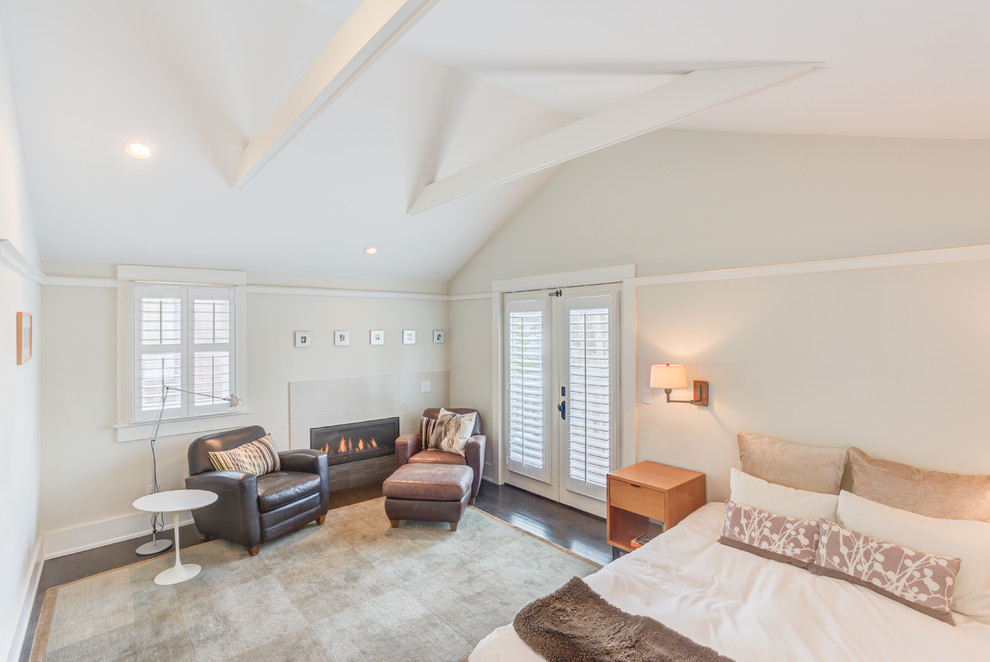 Imagen de dormitorio principal actual de tamaño medio con paredes blancas, suelo de madera oscura, chimenea lineal y marco de chimenea de baldosas y/o azulejos
