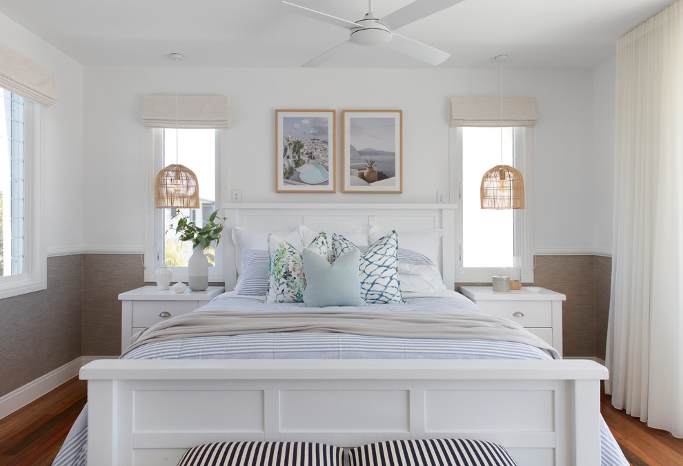 Réalisation d'une grande chambre parentale marine avec un mur blanc, un sol en bois brun et un sol marron.