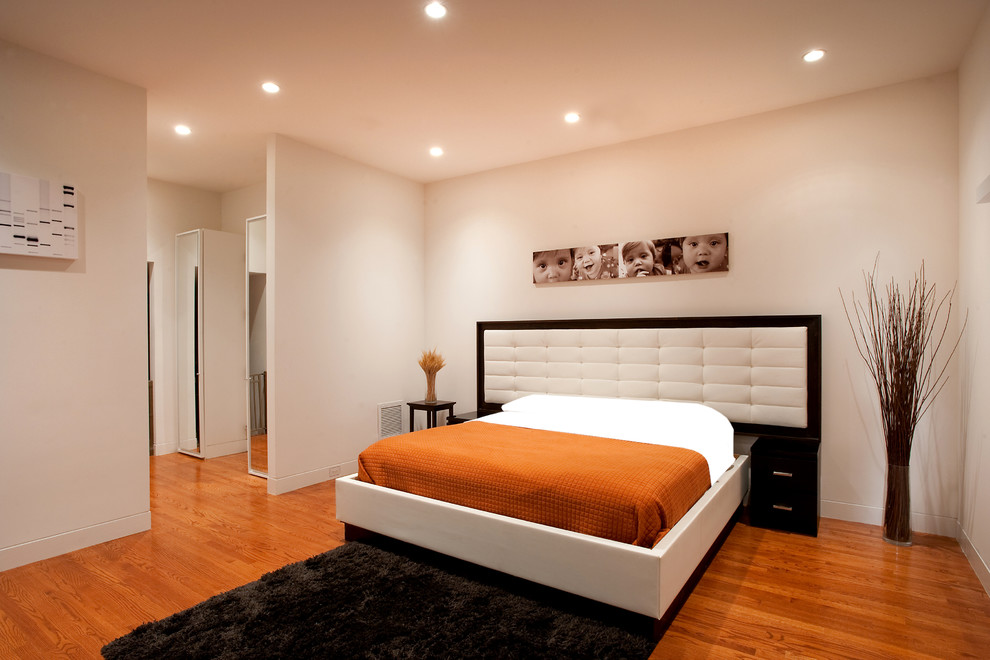 Réalisation d'une grande chambre parentale minimaliste avec un mur beige, parquet clair et un sol orange.