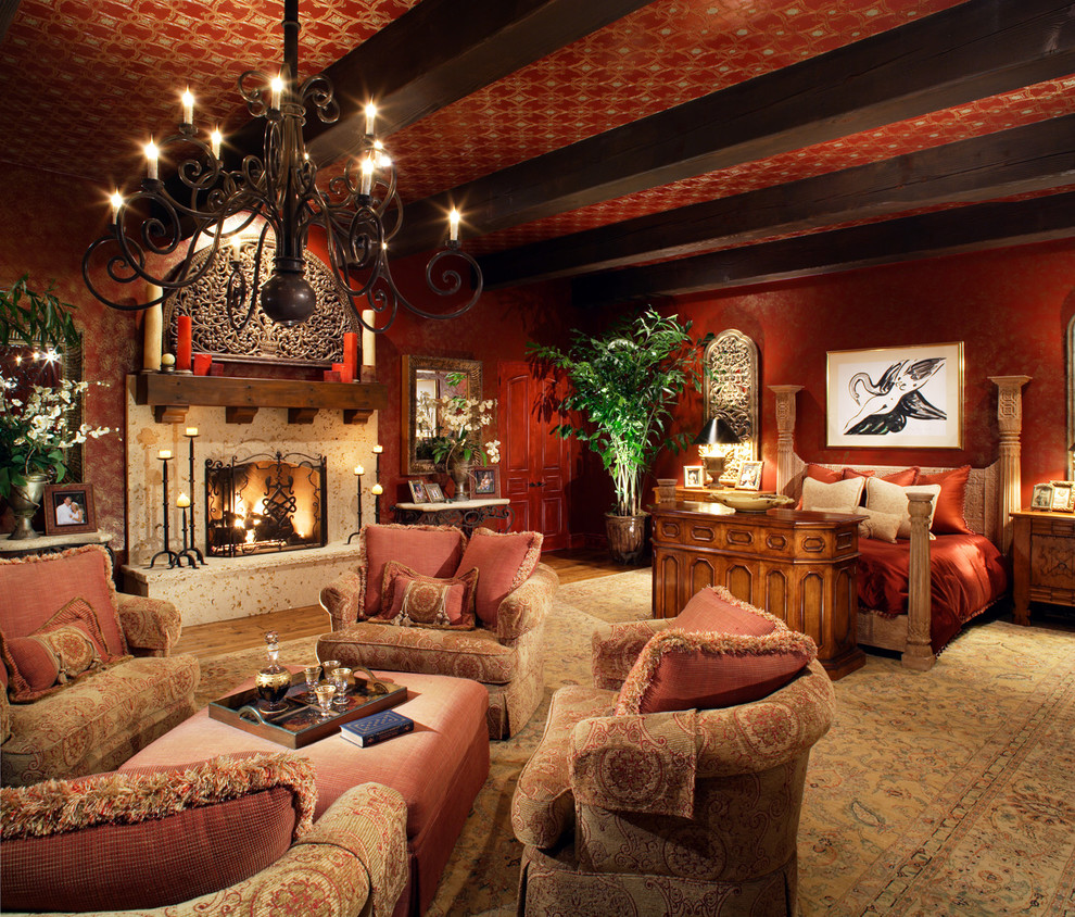 Geräumiges Klassisches Hauptschlafzimmer mit roter Wandfarbe, hellem Holzboden, Kamin, Kaminumrandung aus Stein und braunem Boden in San Diego