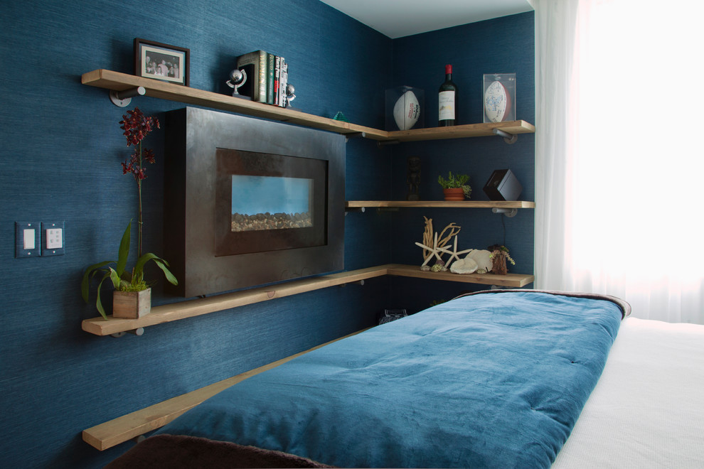 Exemple d'une chambre parentale méditerranéenne avec un mur bleu, parquet clair, une cheminée standard et un manteau de cheminée en métal.