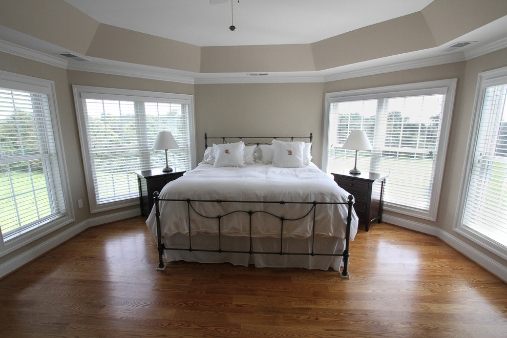 Modelo de dormitorio principal tradicional con paredes beige y suelo de madera en tonos medios