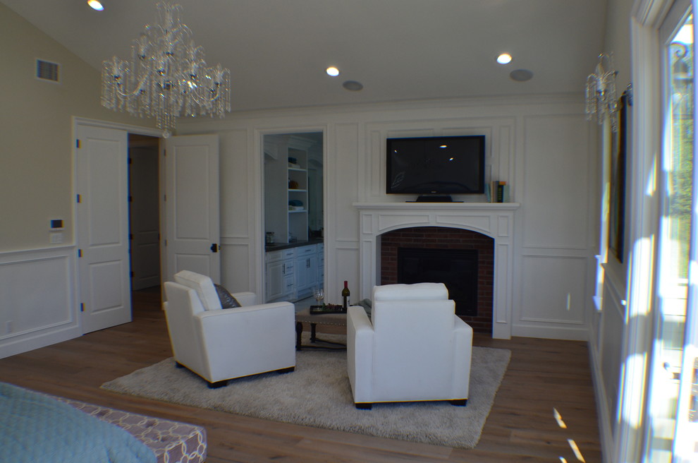 Mittelgroßes Klassisches Hauptschlafzimmer mit beiger Wandfarbe, hellem Holzboden, Kamin, Kaminumrandung aus Backstein und braunem Boden in Los Angeles
