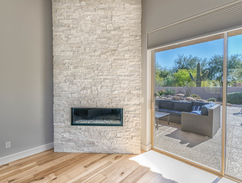 Large transitional master light wood floor bedroom photo in Phoenix with gray walls, a corner fireplace and a stone fireplace