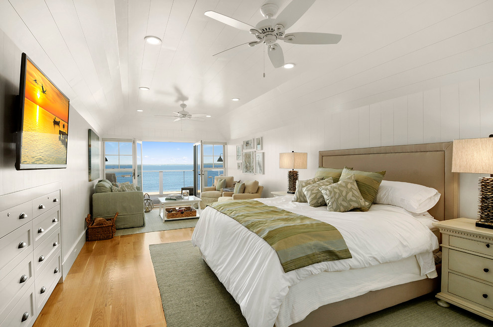 Modelo de dormitorio principal marinero grande con paredes blancas y suelo de madera clara