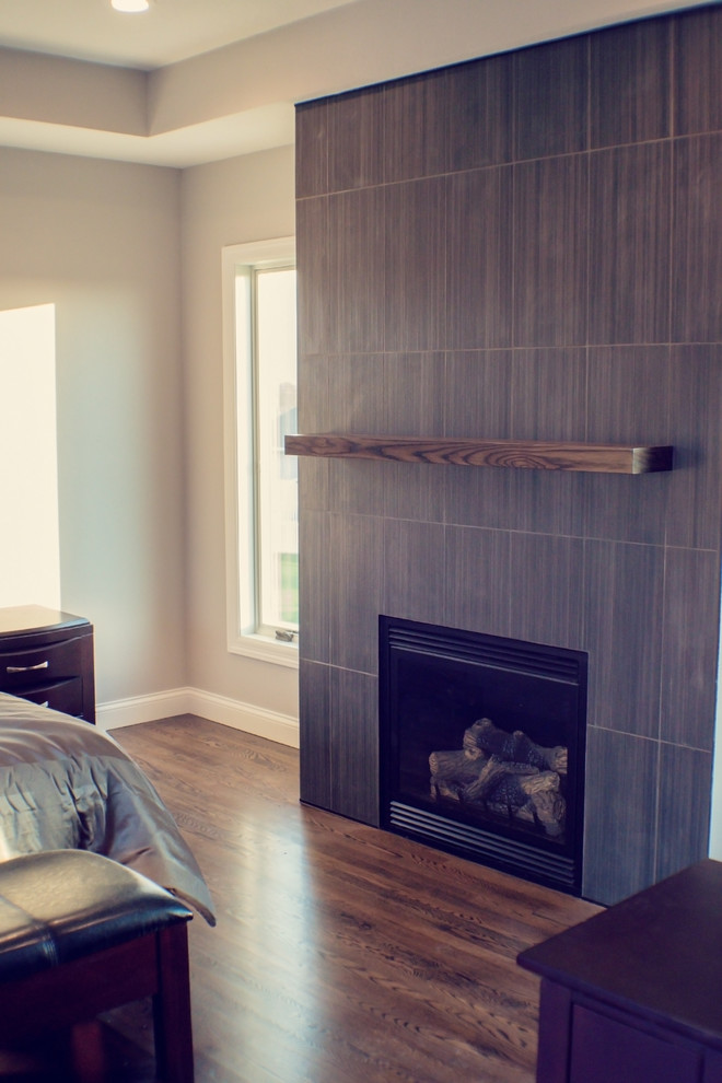 Réalisation d'une grande chambre parentale minimaliste avec un mur beige, parquet foncé, une cheminée standard et un manteau de cheminée en carrelage.