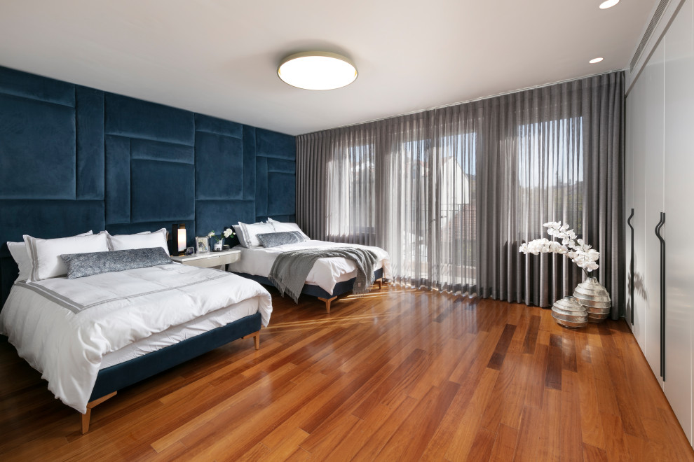 Foto de dormitorio principal actual con paredes grises y suelo de madera en tonos medios
