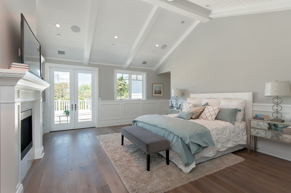 Large elegant master medium tone wood floor bedroom photo in Los Angeles with gray walls, a standard fireplace and a stone fireplace