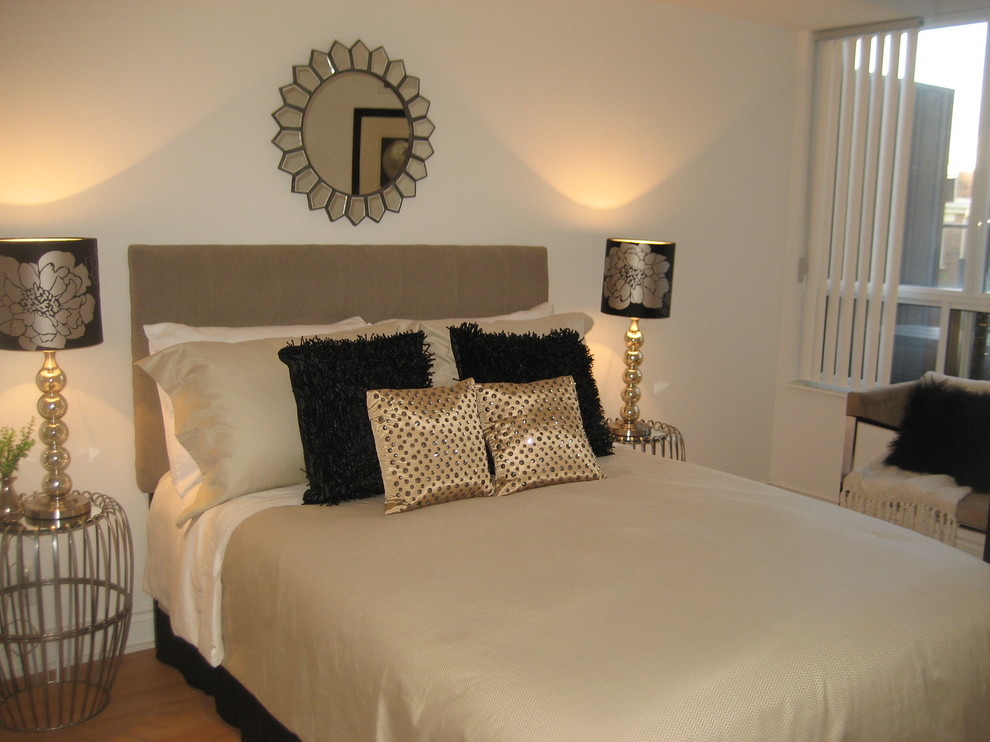 Modelo de dormitorio principal moderno de tamaño medio sin chimenea con paredes beige y suelo de madera clara