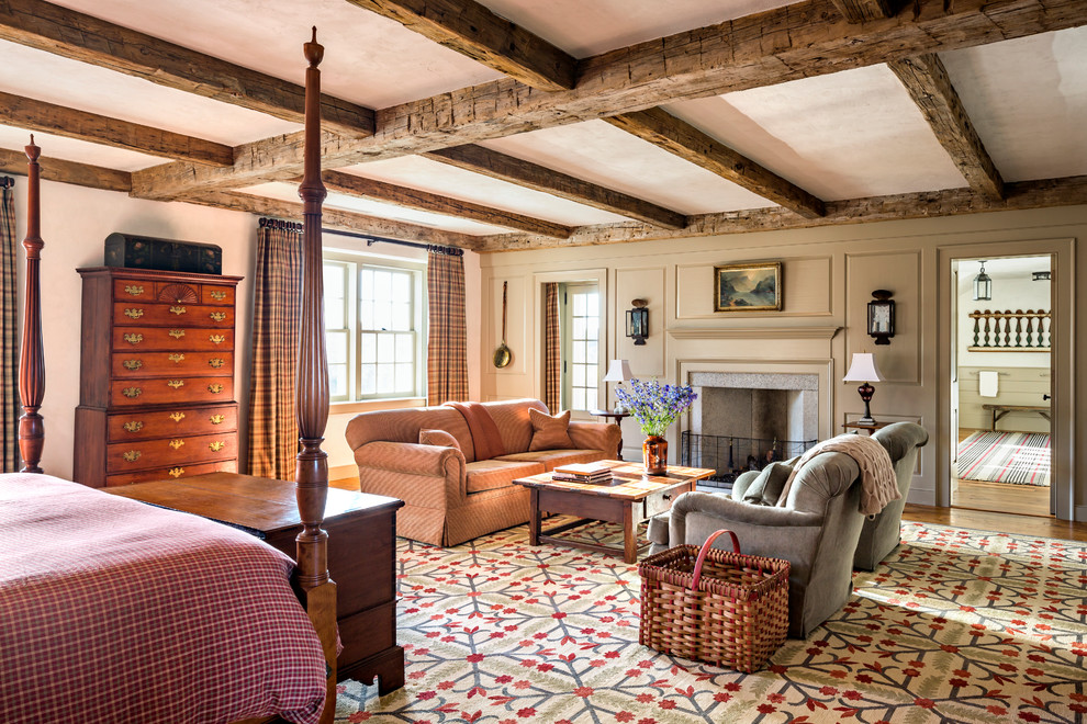 Geräumiges Country Hauptschlafzimmer mit weißer Wandfarbe, braunem Holzboden, Kamin und Kaminumrandung aus Stein in New York