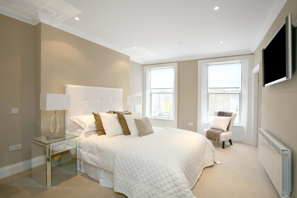 Immagine di una camera da letto contemporanea con pareti beige, moquette, pavimento beige e TV